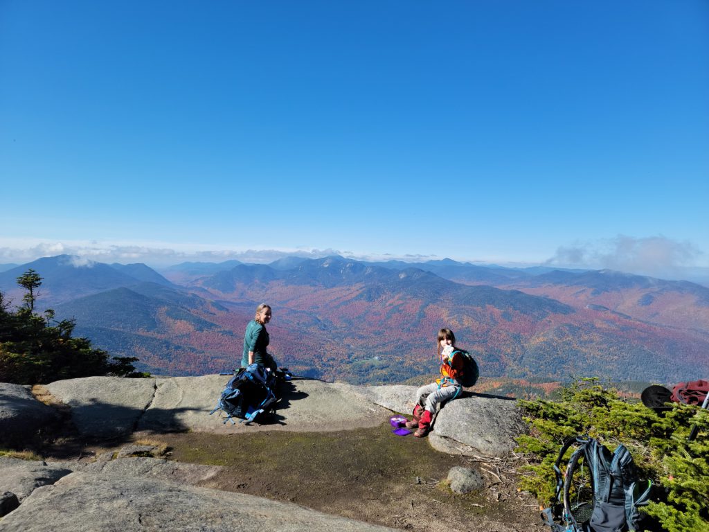 landscape view on top of the mountain with a little girl and mom eating snacks