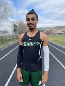 student in a track uniform standing on an outdoor track