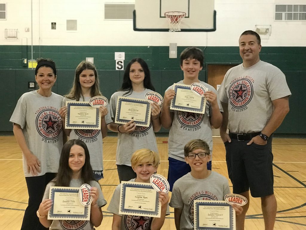 students holding up certificates, three are kneeling and three are standing behind them with two coaches