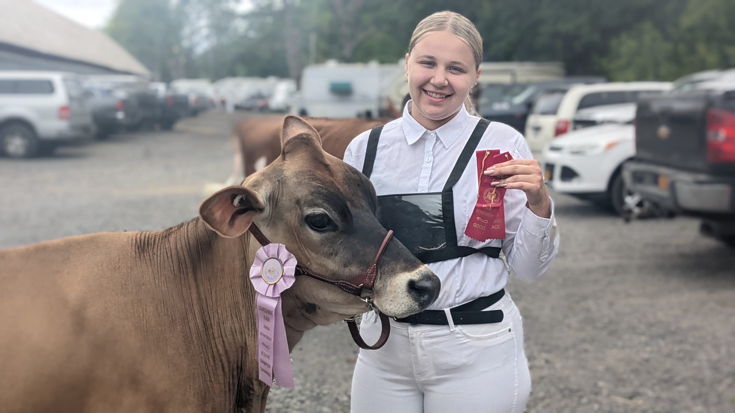 Female students poses with her ribbon and award winning cow.