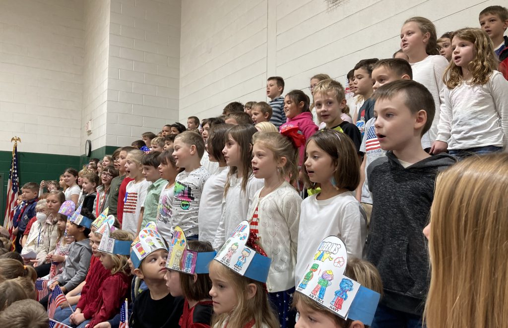 Students stand on bleachers and sing