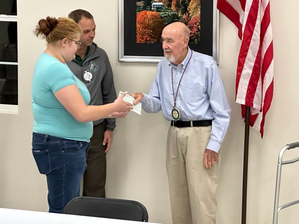 A check is passed between two people while another looks on