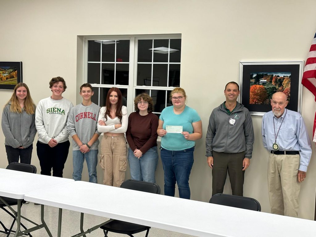 Students pose holding a check