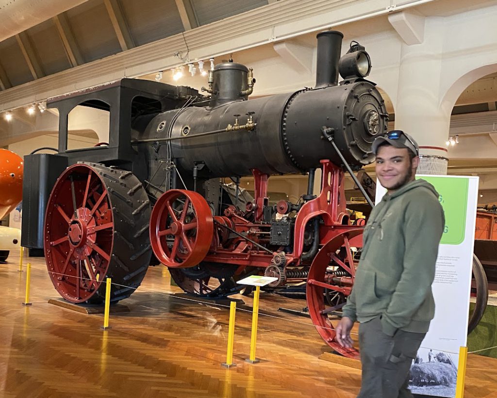 A student stands in front of a large train engine