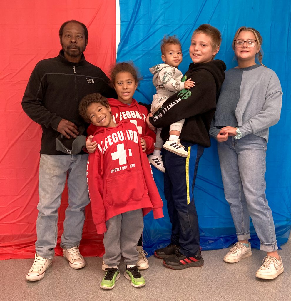A family poses for a photo against a red and blue backdrop