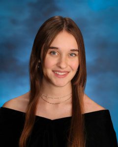 A teen smiles at the camera in a senior class pose.