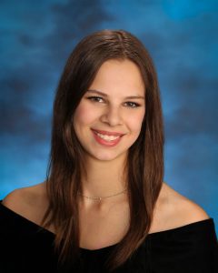 Teenage girl poses for senior class portrait. She is smiling.