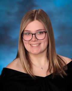 A teen smiles at the camera in a senior class pose.