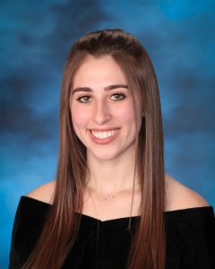 A teen smiles at the camera in a senior class pose.