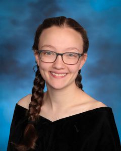 A teen smiles at the camera in a senior class pose.