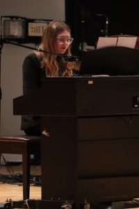 A teen girl plays a keyboard on stage.