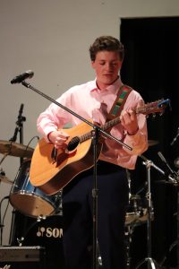 Teen plays guitar on stage