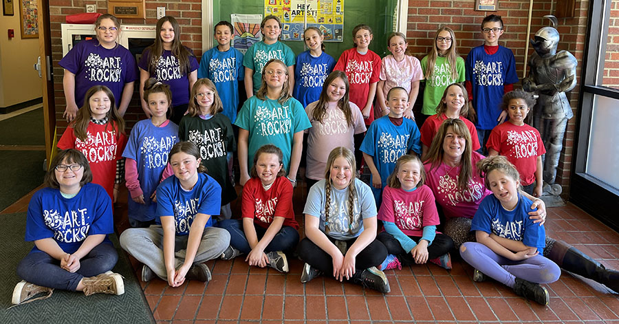 Group of elementary students wearing t-shirts that say "Art Rocks." The shirts are in a variety of colors.