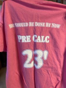 Back of pink t-shirt. It says "You should be done by now. Pre Calc 23."