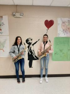 Two teens holding saxophones.
