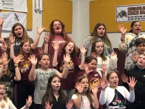 Students sing with their hands raised.