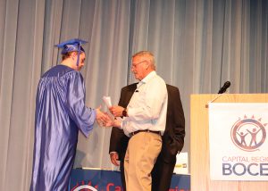 Danny Cater in cap and gown, receiving certificate of scholarship.