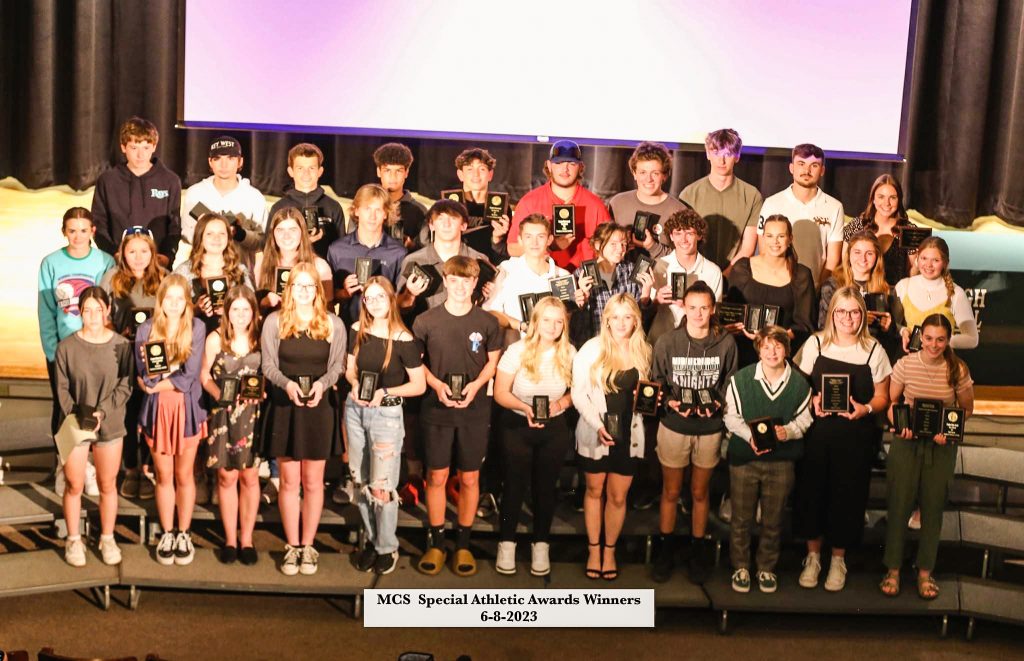 Dozens of student-athletes on stage holding awards.