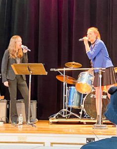 Students singing on stage together.