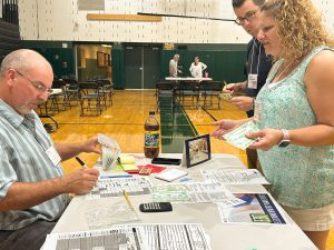 Two adults present papers at a table during poverty simulation.