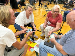 Group of four adults participates in poverty simmulation using play money and transportation vouchers.