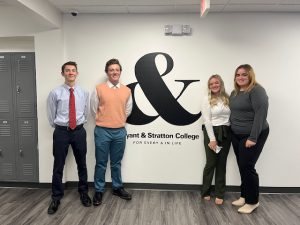 Four members of MCS FBLA club stand in front of Bryant and Stratton logo
