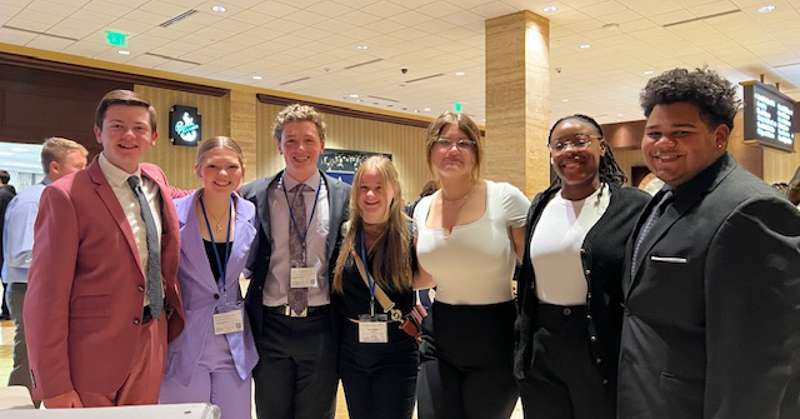 Seven members of FBLA stand with arms around each other at national conference.