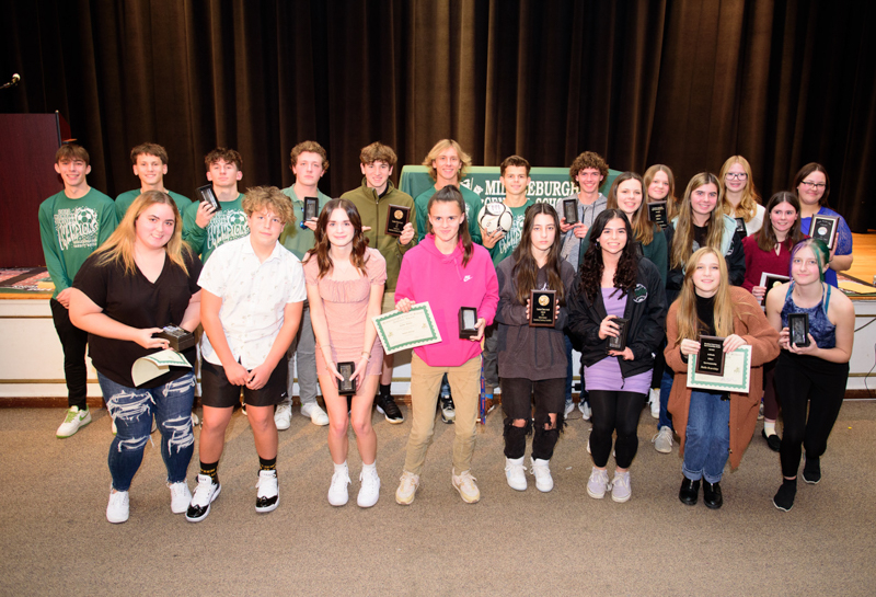 Student athletes stand in a group. They are holding their awards