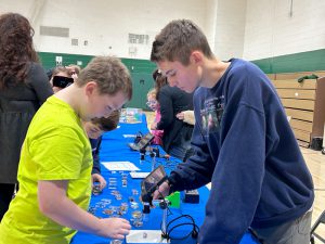 High school student helps elementary student with microscope