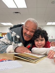 Veteran and child at a table with an open book in front of them.