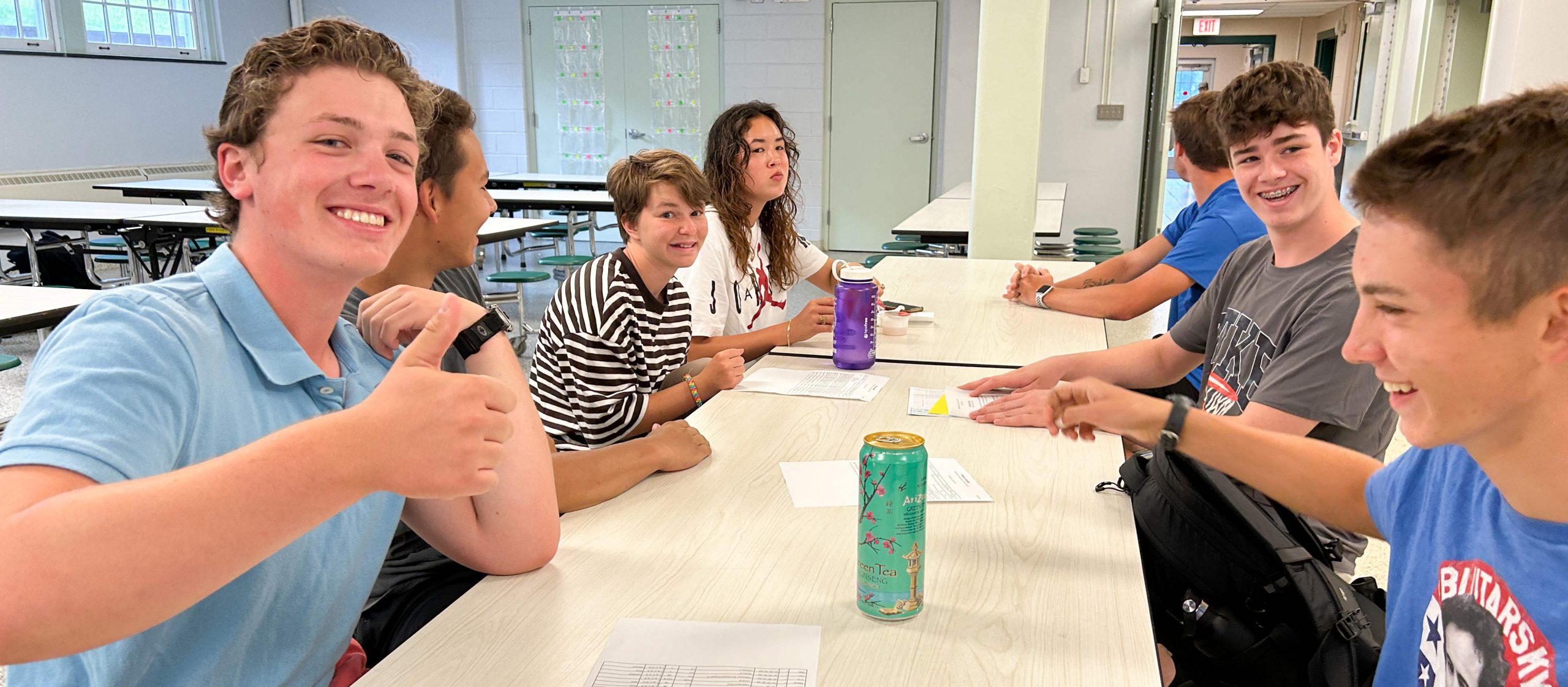 Seven high school students sitting at a table talking