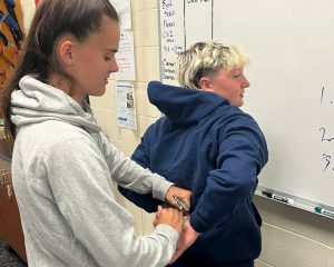 Student Cierra DuPont practices putting handcuffs on another student.