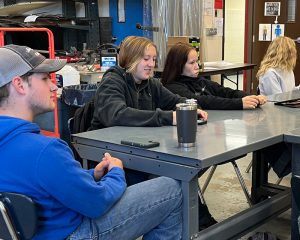 Student Logan Chichester sits with other students at a table.