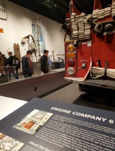 Students look at 911 exhibit at NYS Museum. Firetruck in the foreground.