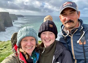 Amy Irwin with her daughter and husband. There is a body of water in the background.