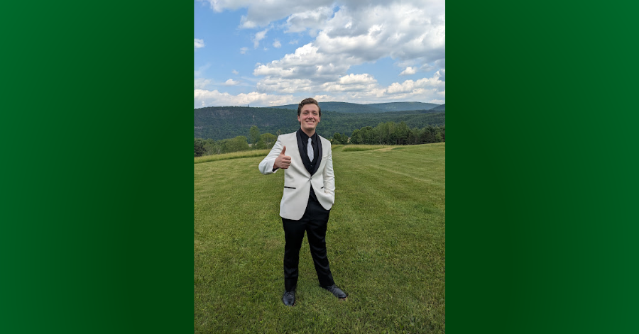 Teen stands in front of mountain in formal attive and gives a thumbs-up