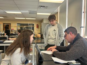 Principal looks at paper with students.