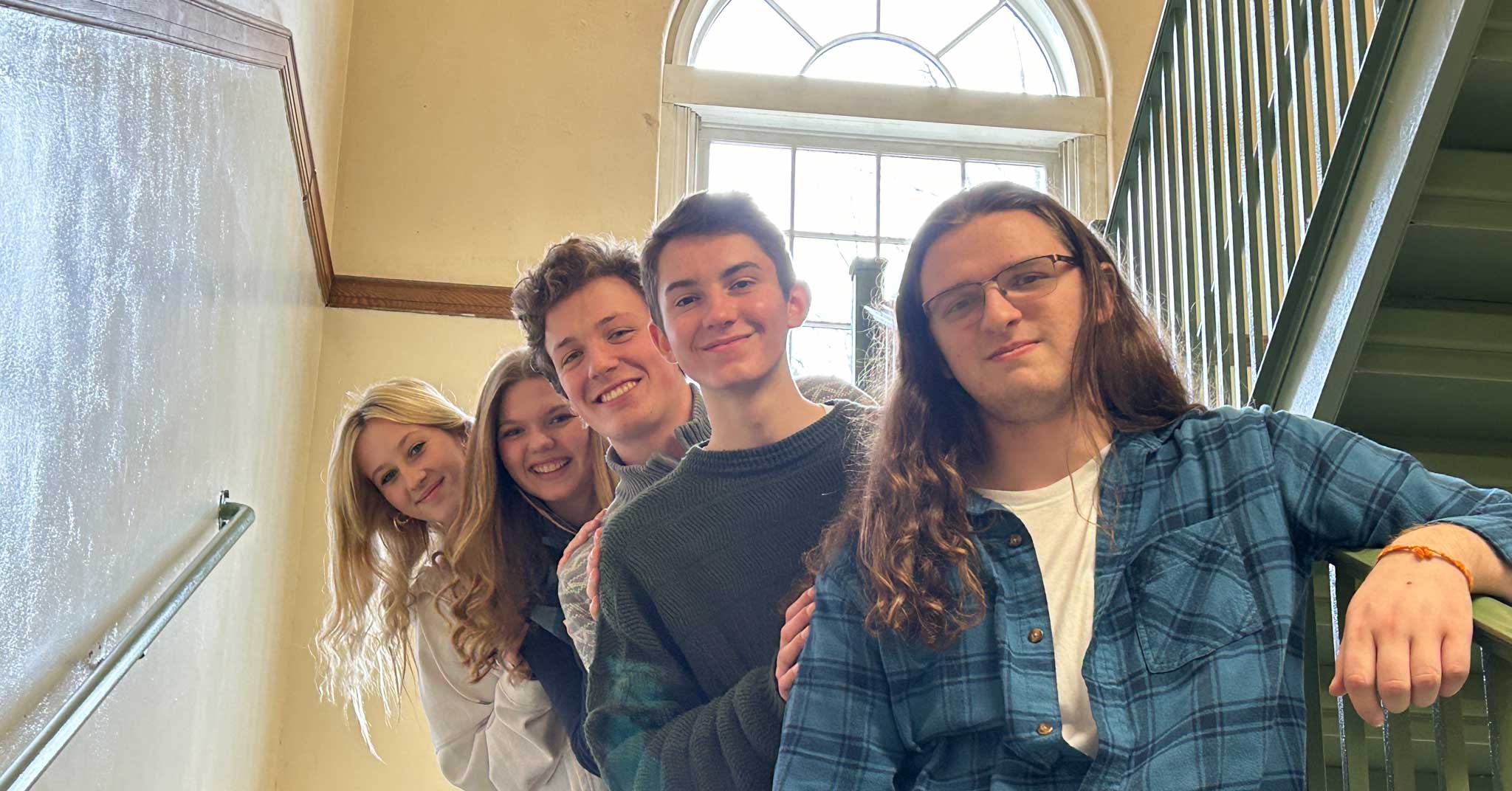 Five students standing in fan formation on stairs