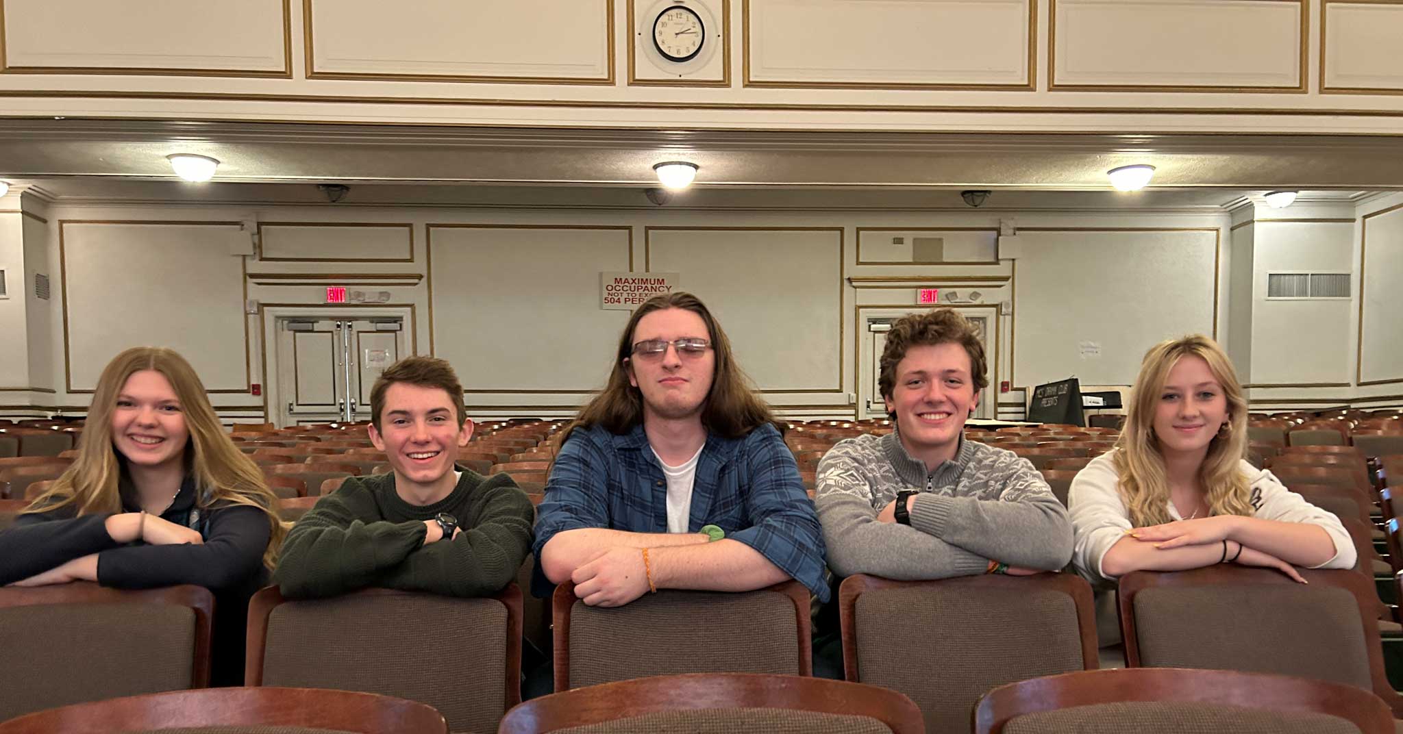 Five students sitting in auditorium.