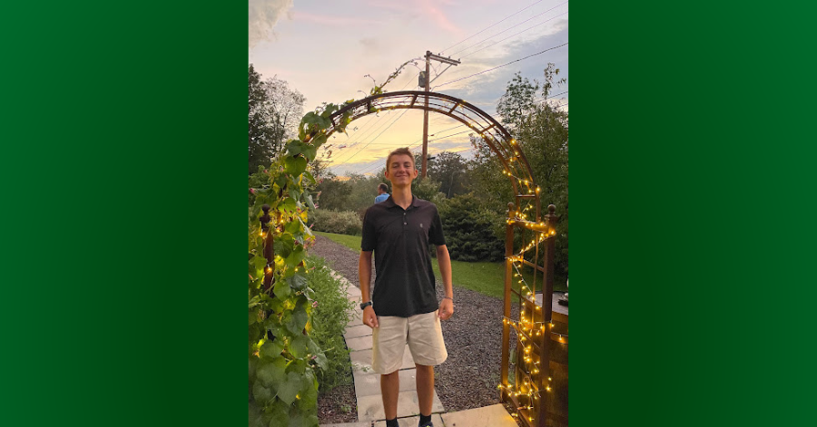 Teen stands beneat flowered arch.