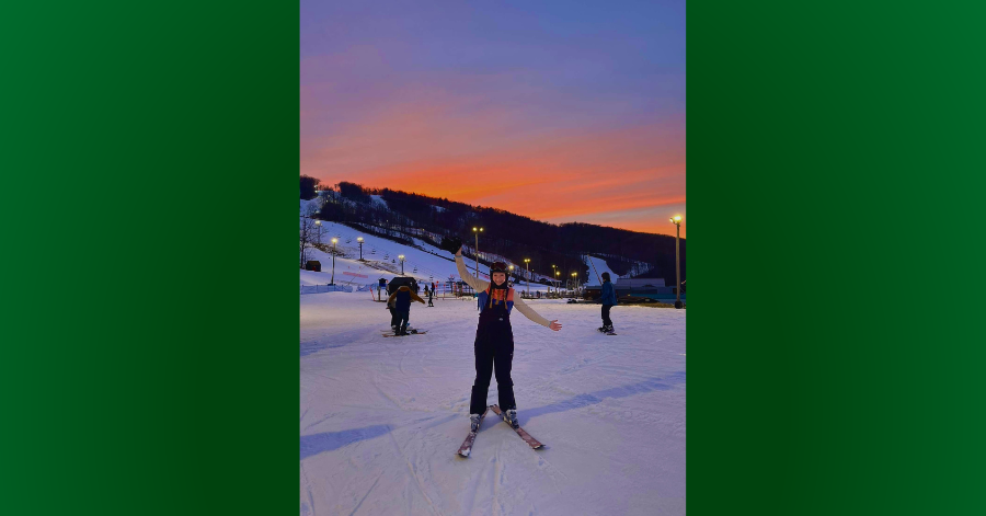 Teen on ski slope with sunset in background.