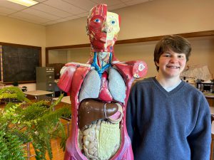 Gabrielle Armlin stands next to a model of the human body.