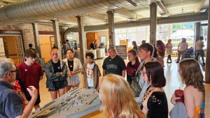 Students listen to man discuss art exhibit.