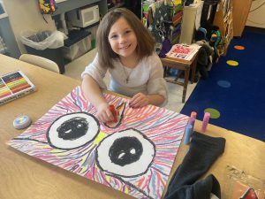 Elementary student creating a large owl on a canvas.