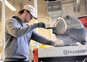 Teen student using a saw.