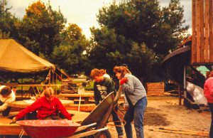 Community members with wheelbarrows at construction site.