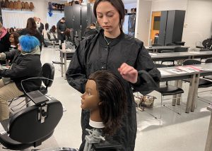 Student works on a cosmetology mannequin.