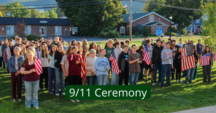 Junior and senior high students, some holding flags, stand on the lawn.