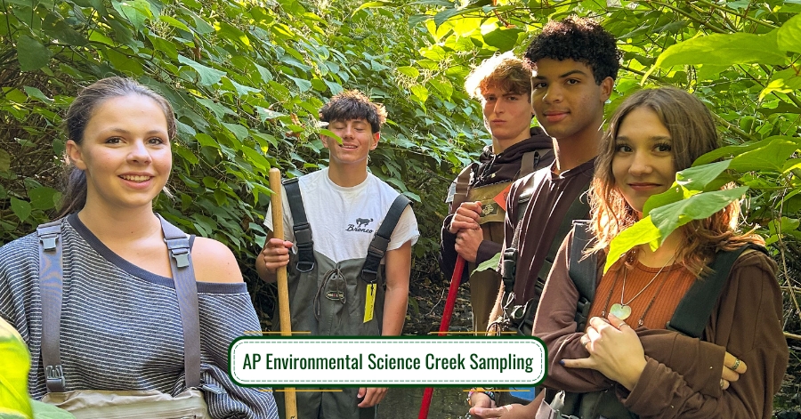 Five high school students wearing overalls in leafy area. Some are holding tools.