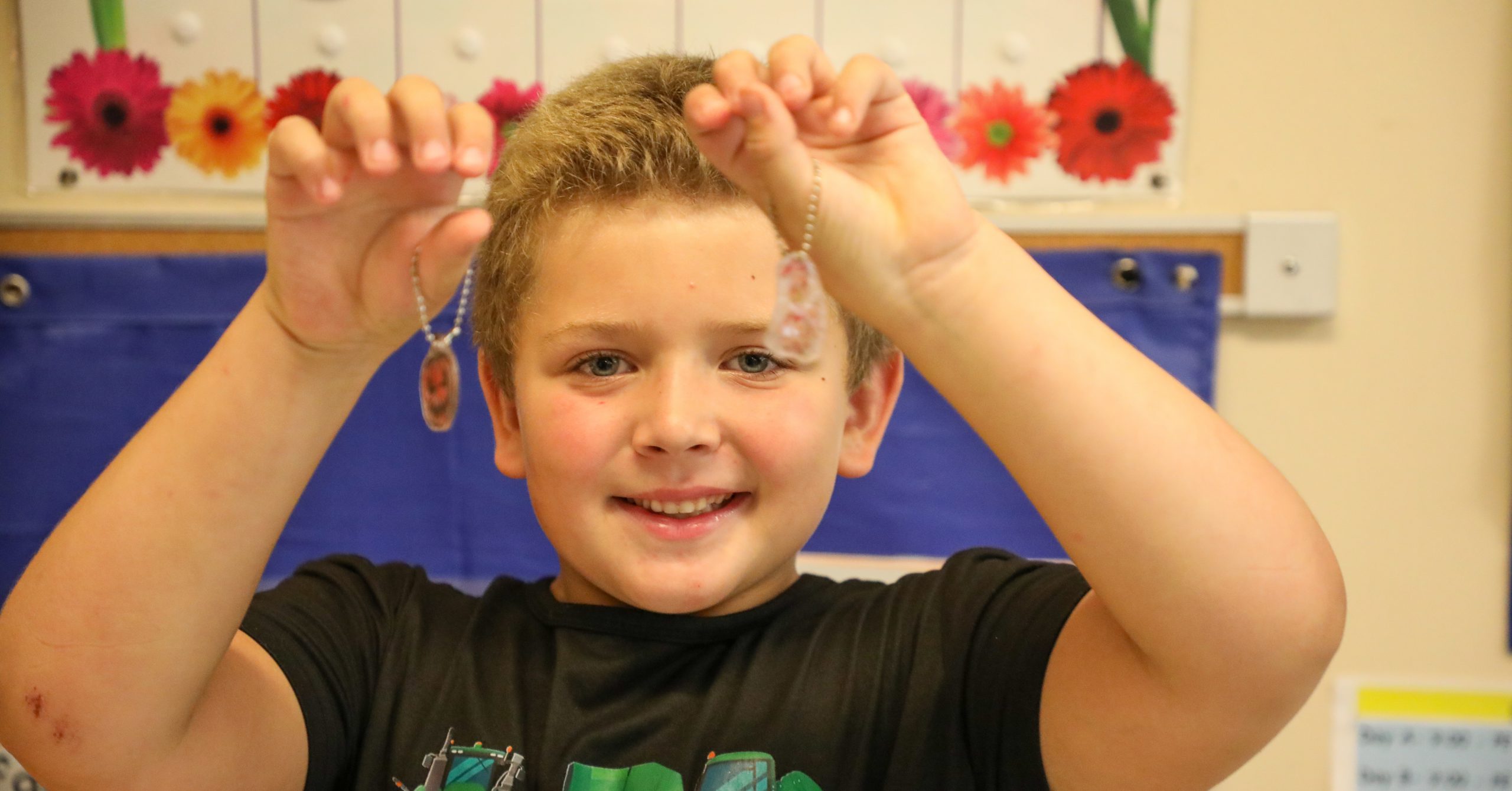 Child holds up two bracelets. 